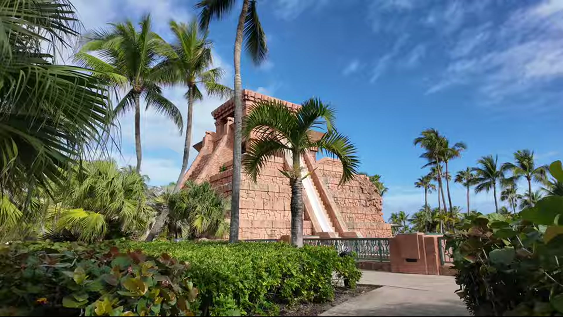 Mayan temple themed water slide surrounded by palm trees at a tropical resort.